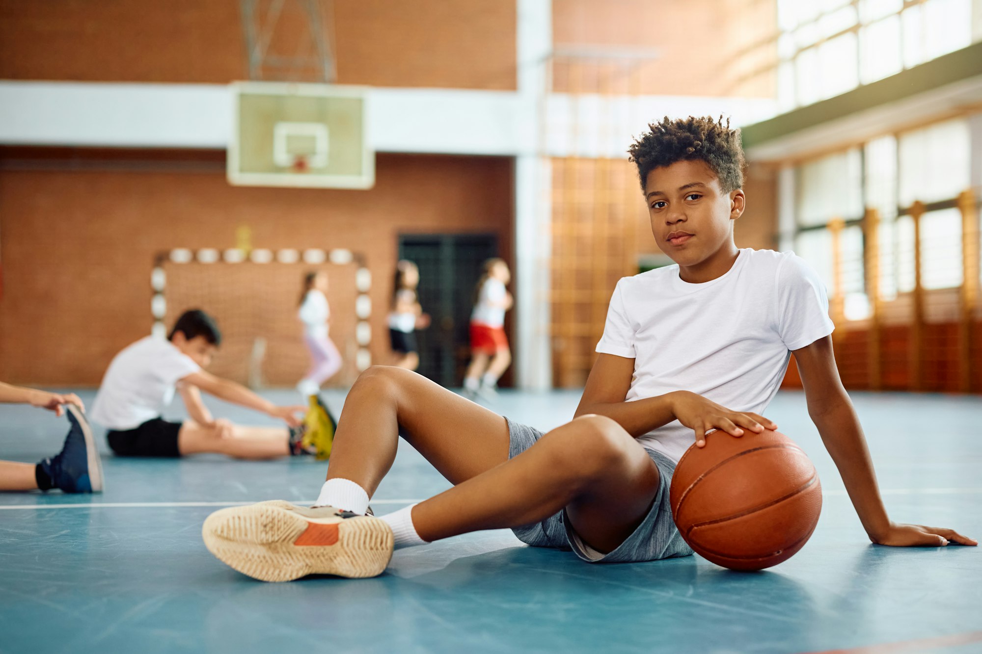 Black elementary student with basketball during PE class looking at camera.