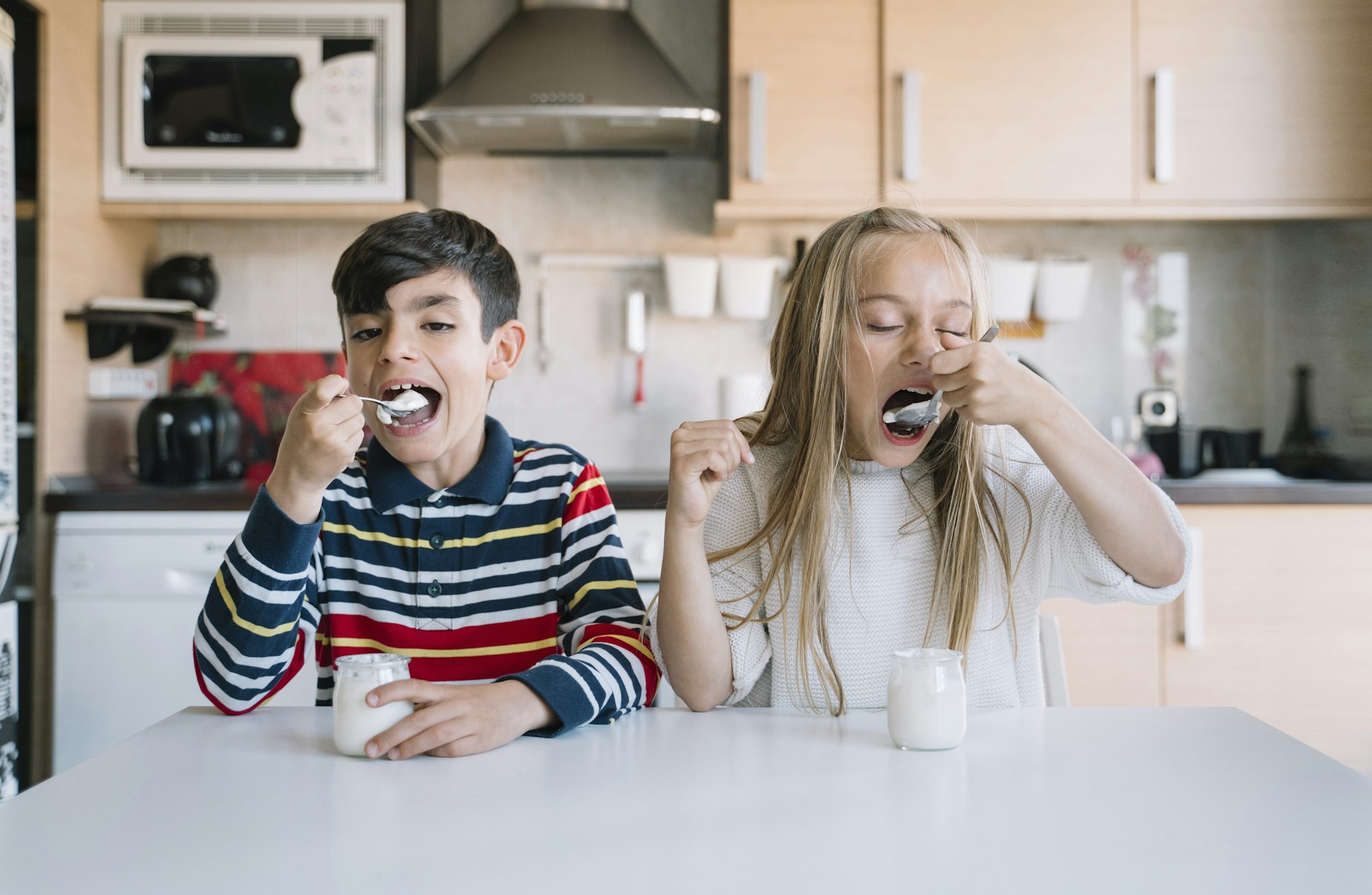 Two kids eating a healthy yoghurt breakfast